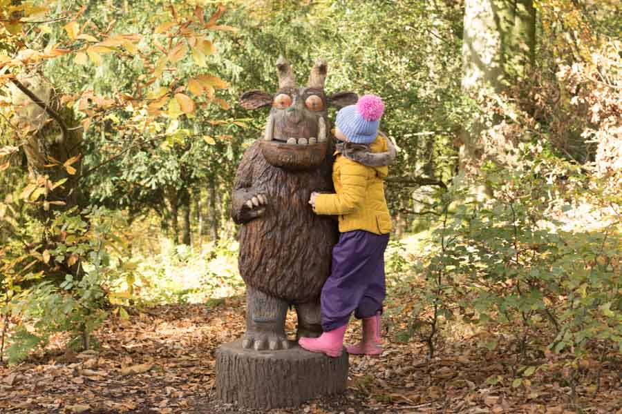 Child hugging a Gruffalo sculpture