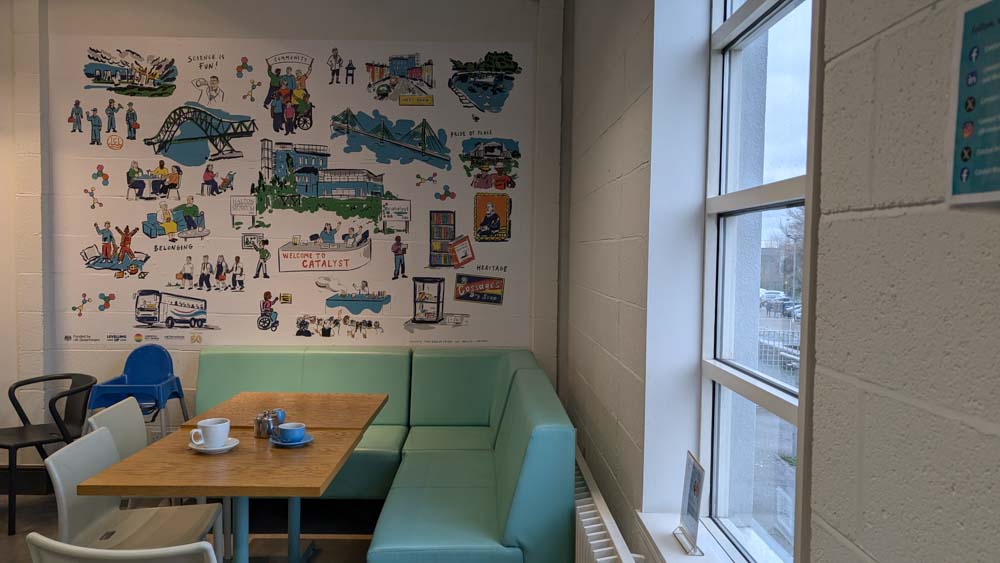 Bench seating and a table in front of a white wall with lots of science themed images on it