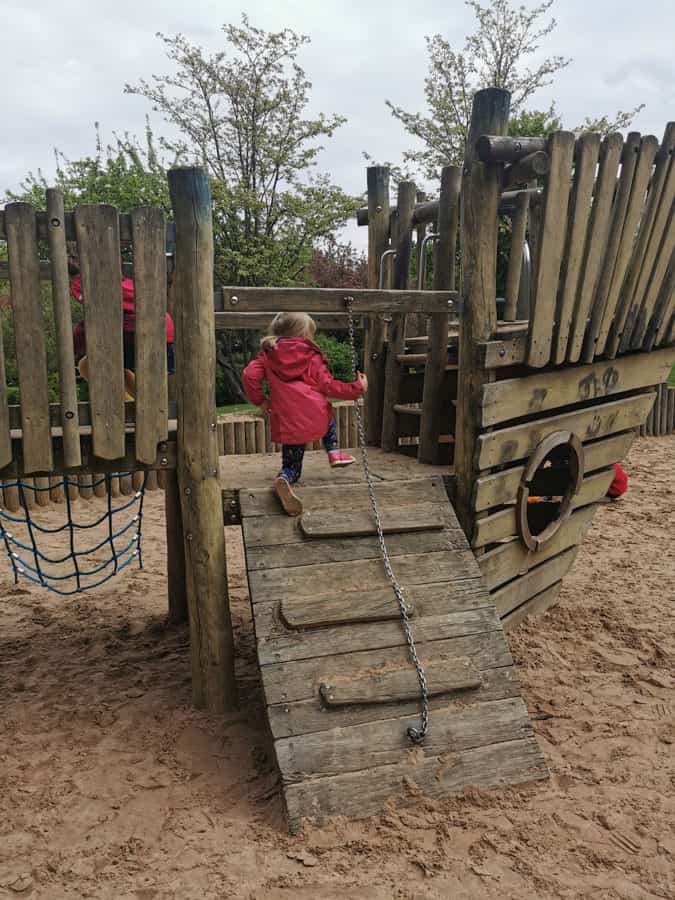 Child climbing a wooden play ship
