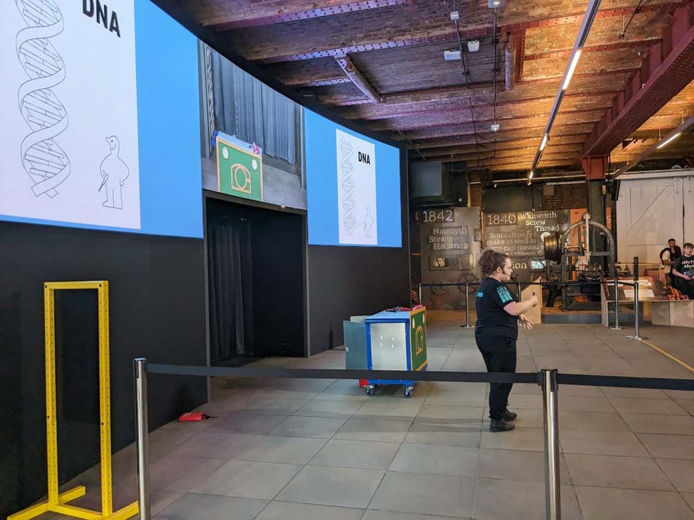 Large space with screens down one side and lady presenting in the middle