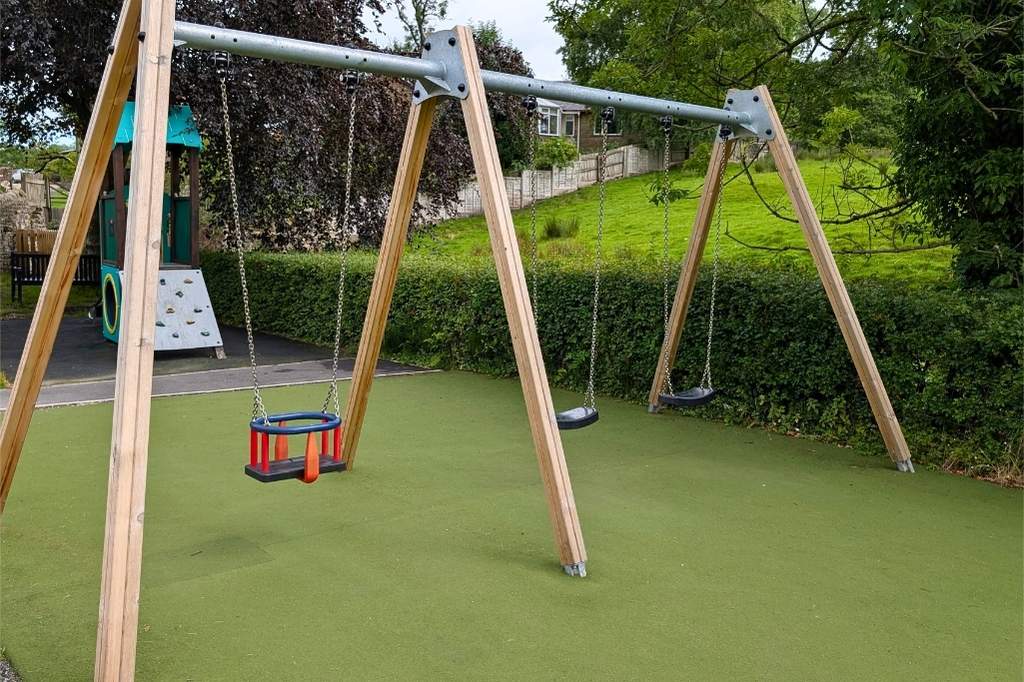 Wooden swings and toddler climbing frame behind