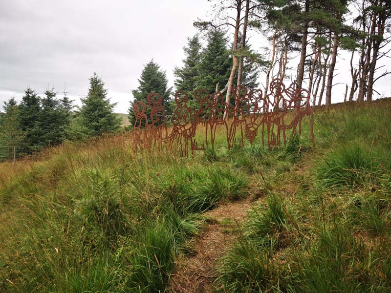 Metal witch sculptures on a grass hill