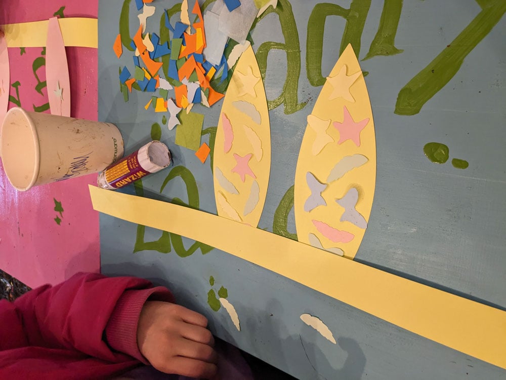 Card ears being decorated with glue and bits of coloured paper