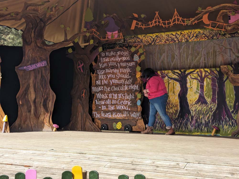 Woman on stage with a sign with lots of text on it