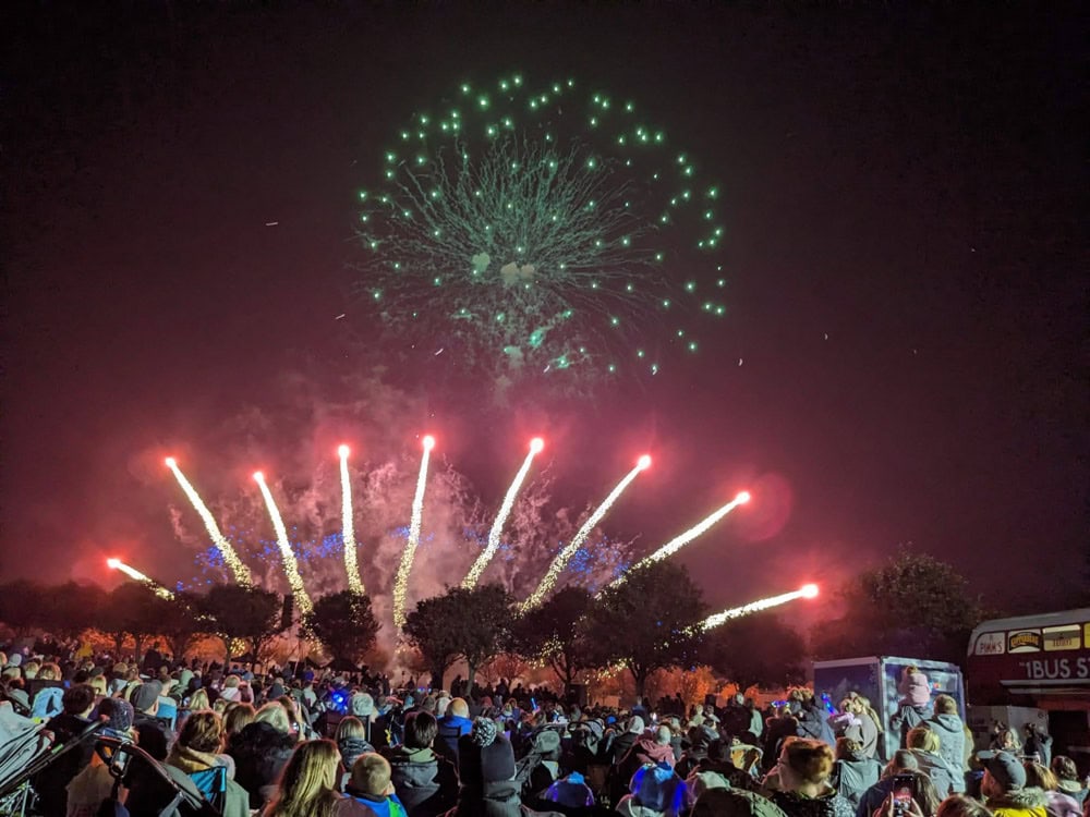 Red and green fireworks over a large crowd