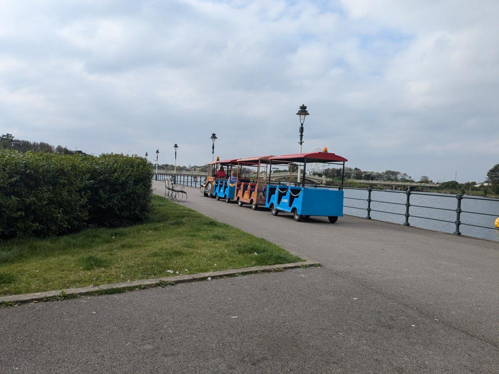 Colourful land train on a path by a lake