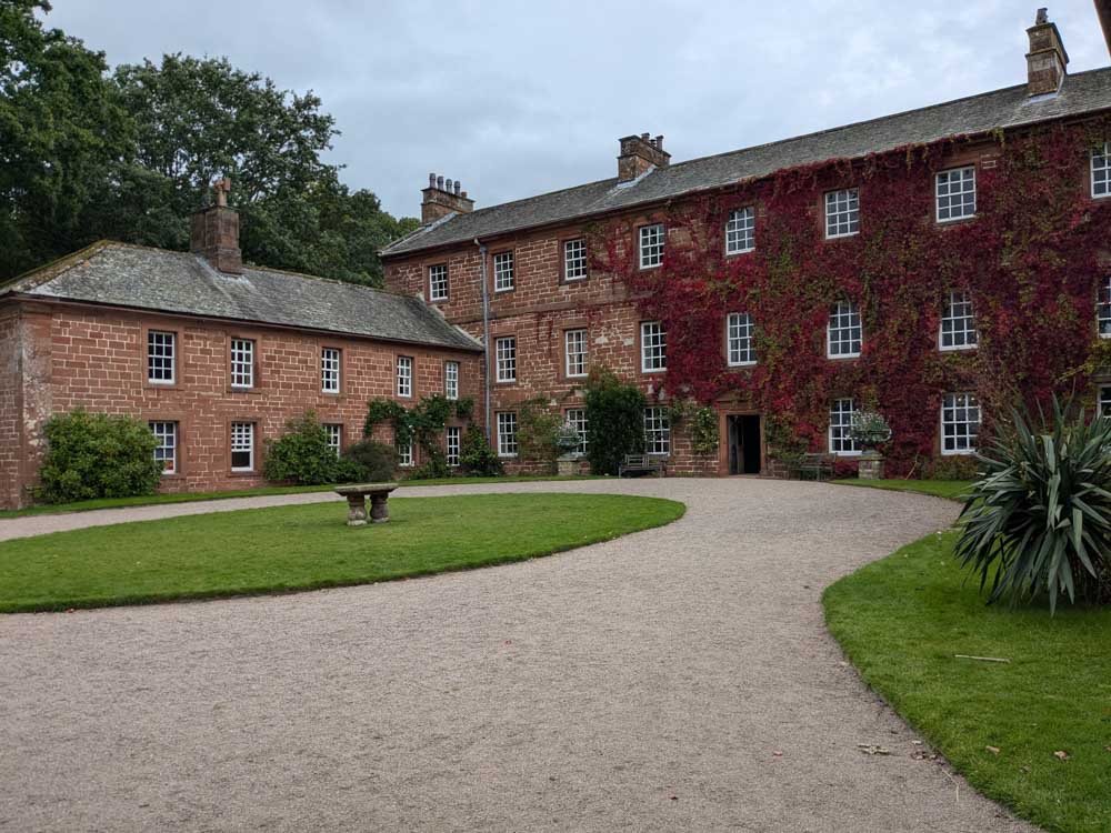 Red brick mansion house with curving gravel drive and lawn in front