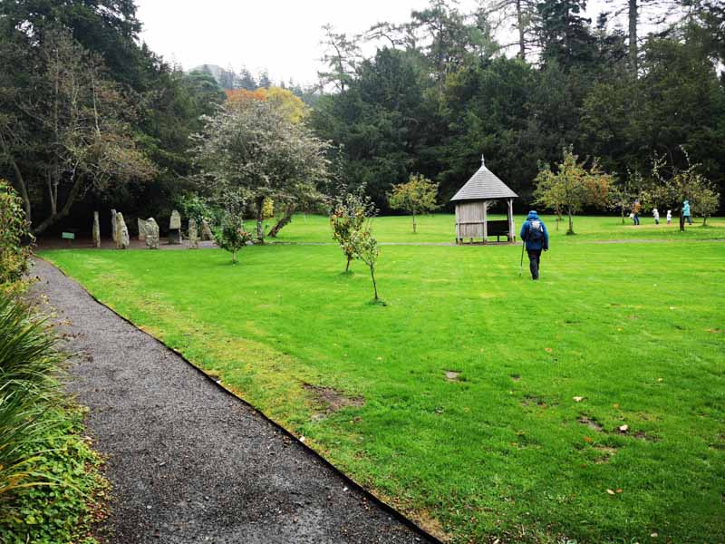 Large lawn with man walking towards wooden hut
