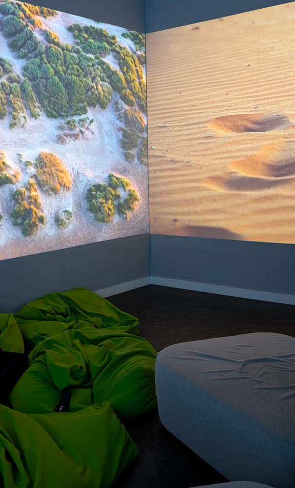Green bean bags on the floor and screens with nature photos on the walls
