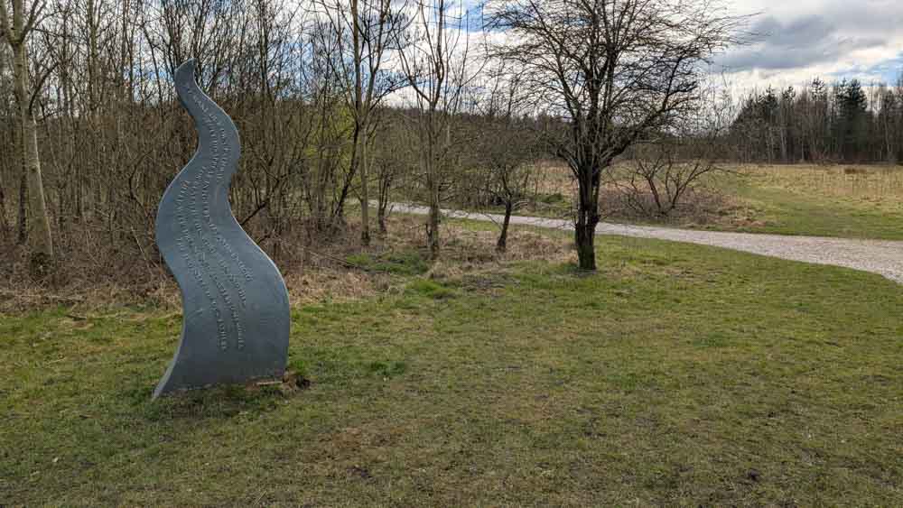 flame shaped metal sculpture on grass with trees behind