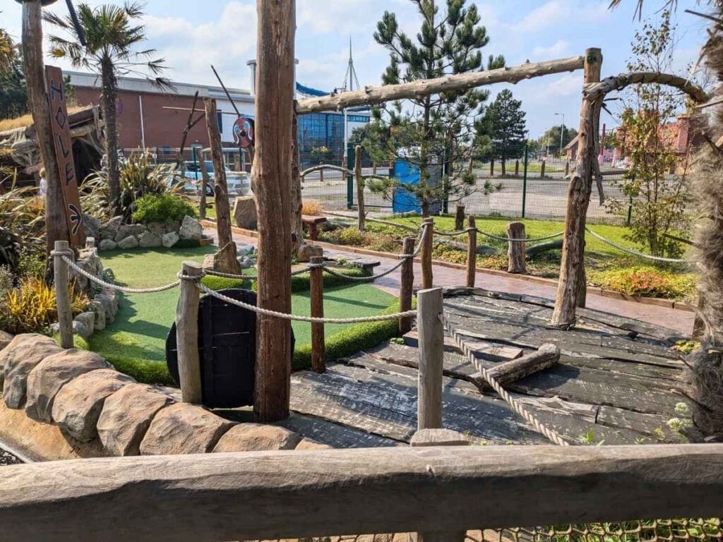 Crazy golf course with lots of wood and a car park behind