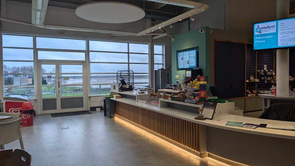 Counter of food in a large airy room with windows across one wall