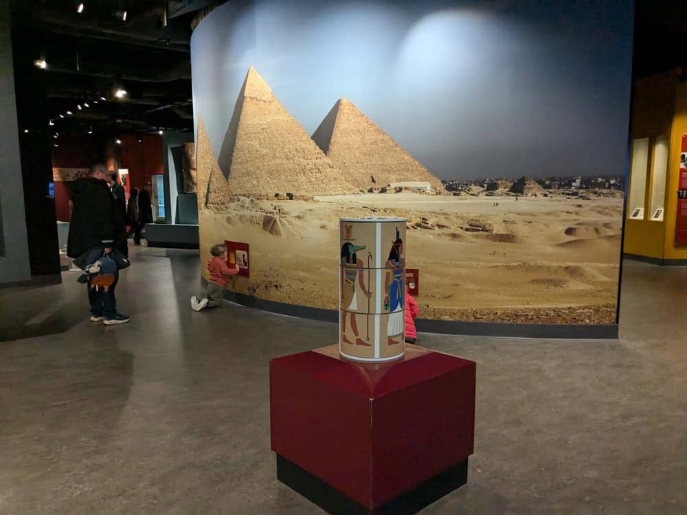 wall covered in picture of the Egyptian pyramids with interactive elements and kids playing